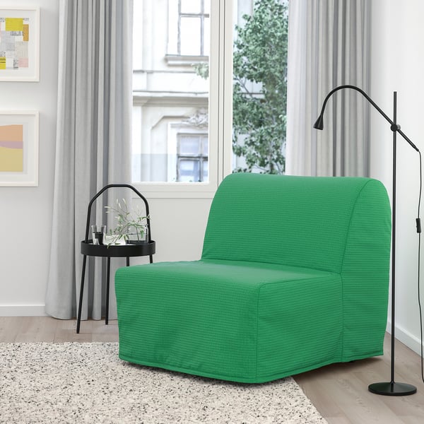 Silla-cama LYCKSELE LÖVÅS de color verde brillante cerca de una gran ventana. Diseño moderno y cuadrado. Más pequeño que la alta lámpara de pie negra que tiene a su lado.