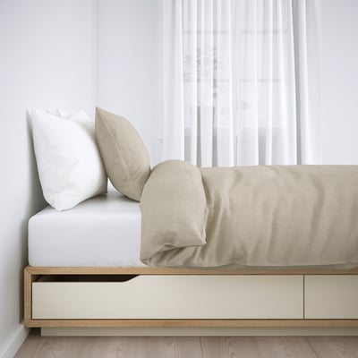 Cama de madera con cajones de almacenamiento, sábanas beige y almohadas blancas. Se incluyen viga media y somier.