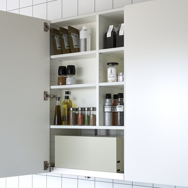 Un moderno armario de pared blanco con tres estantes que almacenan diversos artículos de cocina como especias, aceites y bolsos.