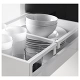 Cajón de cocina blanco y negro abierto, mostrando platos organizados: tazas, tazones y platos en cajón blanco brillante, con divisor para platos.