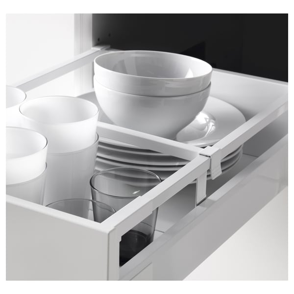 Cajón de cocina abierto que muestra platos organizados: tazón grande, tazas, platos, cristalería y bandeja para cubiertos.