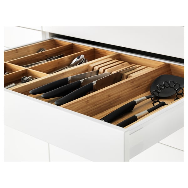 Cajón de cocina abierto con utensilios, cuchillos y tablas de cortar en organizador de madera.