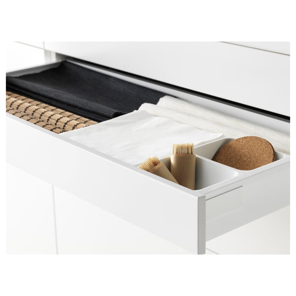 Cajón de cocina blanco abierto que muestra compartimentos organizados, incluidos cepillos y posavasos, ideal para la limpieza y el orden.