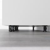 Patas ajustables negras que soportan el gabinete blanco para mayor estabilidad en suelos irregulares.