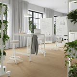 Moderna sala de conferencias con mesas altas y portátiles, luz natural.