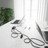 Escritorio de oficina moderno con computadoras portátiles, regletas de enchufes y cables, con una configuración ergonómica y una solución de administración de cables.