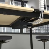 Moderna mesa de conferencias con altura ajustable, con gestión de cables incorporada y soporte para las piernas para mayor comodidad durante las reuniones.