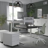 Moderna oficina en casa con escritorio blanco MITTZON, silla verde, monitores duales y cajones de almacenamiento. Diseño elegante y limpio.