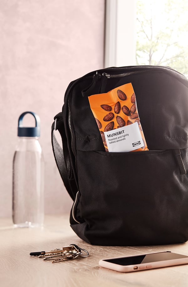 Mochila con bocadillo naranja empaquetado con la etiqueta MUNSBIT en una mesa cerca de las llaves y el teléfono.