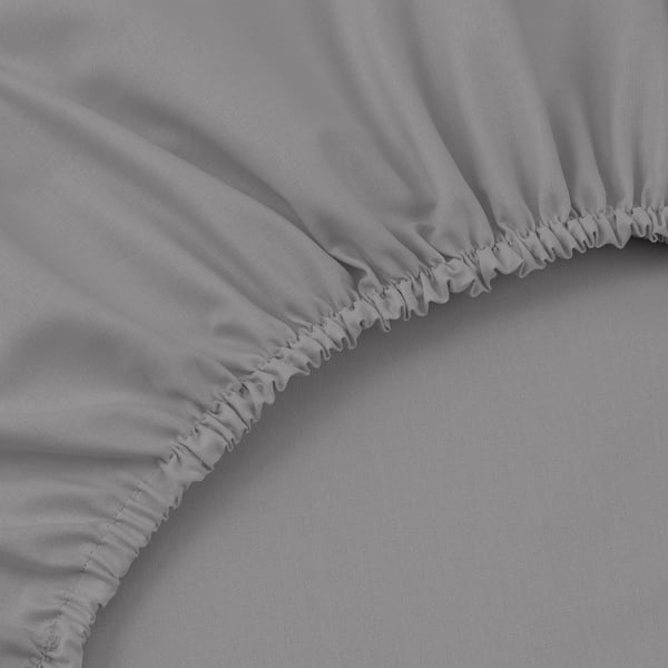 Primer plano de una suave sábana de algodón gris claro con dobladillo elástico, que resalta la textura fina y la artesanía.