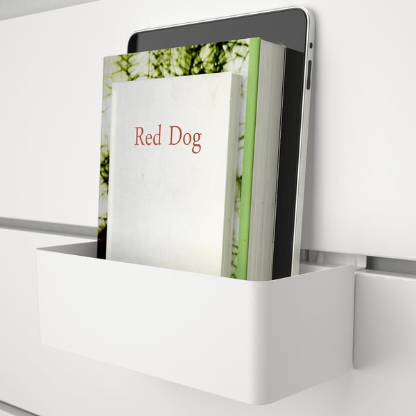 Una tableta y un libro titulado Red Dog se encuentran en un organizador blanco montado en la pared, demostrando una solución de almacenamiento y exhibición para dormitorios.