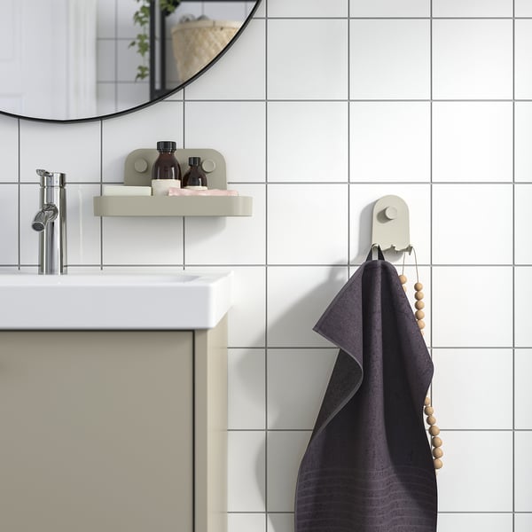 Moderno baño gris con gancho de pared ÖBONÄS, toalla gris, estante flotante, espejo y grifo.
