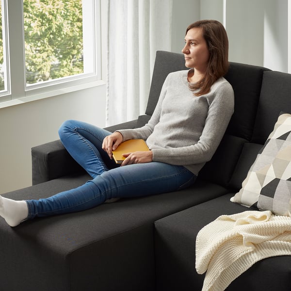 Mujer en sofá ajustable, libro de lectura. O, para mantenerse más cerca del original: mujer en seccional ajustable, leyendo.