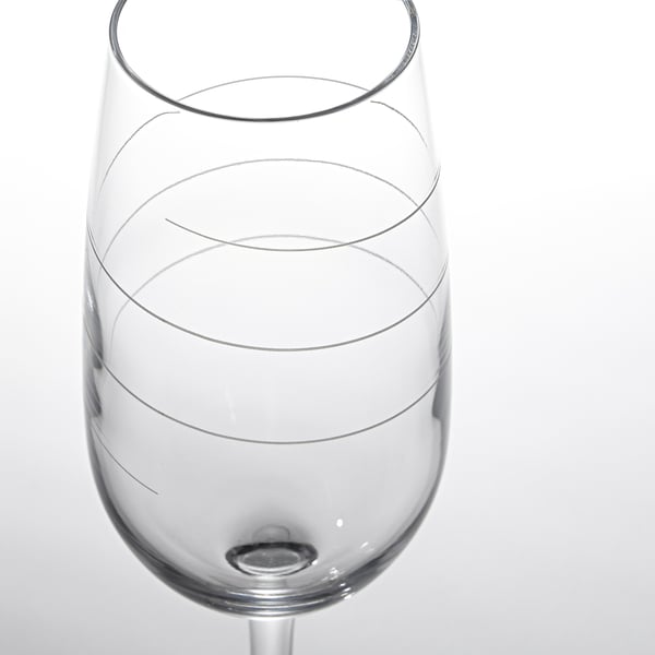 Primer plano en blanco y negro de una copa de vino vacía con intrincadas líneas de diseño, que resaltan su claridad cristalina y su elegante tallo.