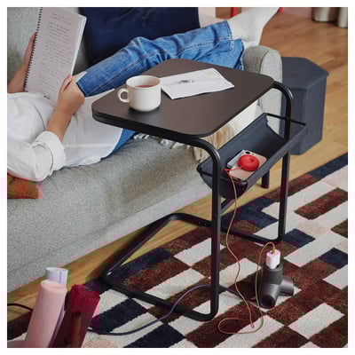 Una mesa auxiliar y de centro OLSERÖD en color negro con bolsa de tela, diseñada para un uso multifuncional en espacios habitables.