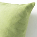 Primer plano de cojín verde reciclado, textura suave, variaciones de color naturales.