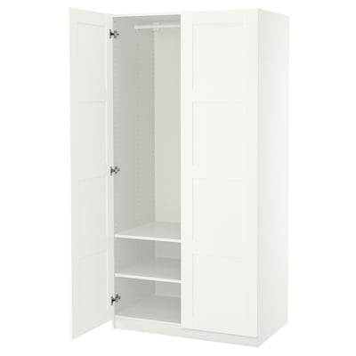 Un armario blanco de ikea PAX con una puerta abierta, que deja ver estantes vacíos y una barra para colgar.