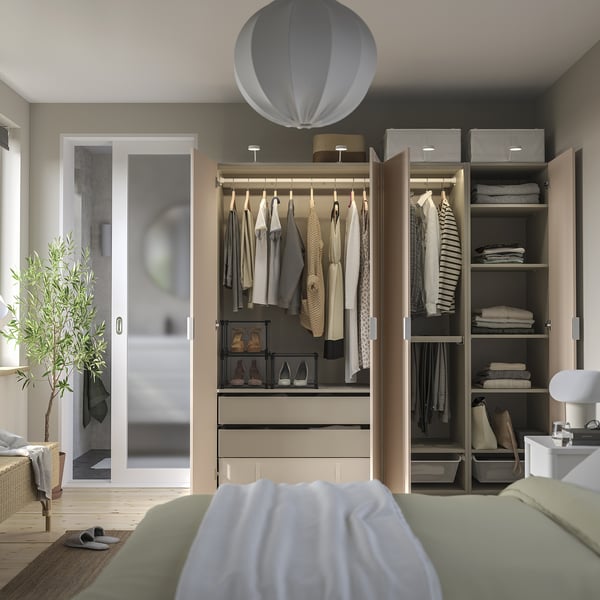 Dormitorio moderno con armario abierto y cama blanca con sábanas verdes.