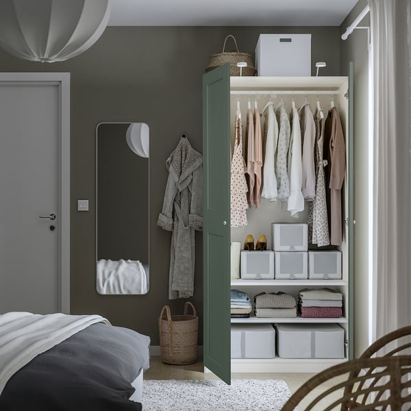 Dormitorio con armario abierto: ropa, cajas, cestas, espejo al lado de la puerta.