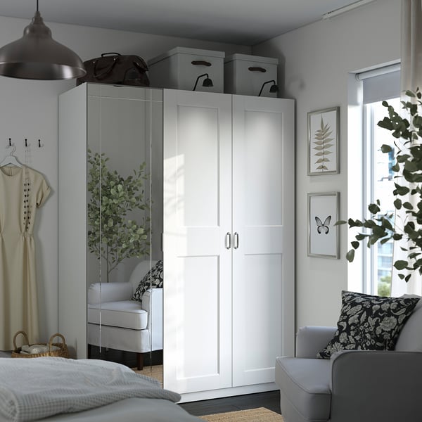 Dormitorio moderno con armario PAX, blanco, paneles de espejo, grande, junto a una silla y ventana acogedoras.