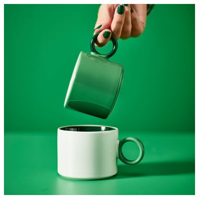 Dos tazas verdes y blancas con asas circulares, colores contrastantes.