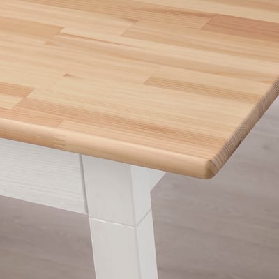 Mesa de comedor de madera llamada PINNTORP, capacidad para cuatro personas, patas blancas, tapa de madera natural. Estilo escandinavo.