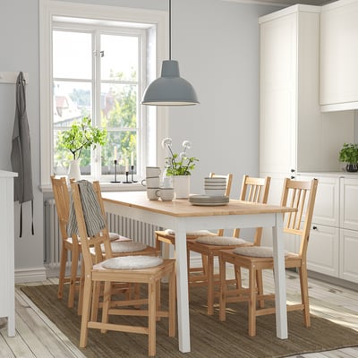 Cocina moderna con mesa, sillas, alfombra y lámpara PINNTORP, rodeada de armarios y un gran ventanal.