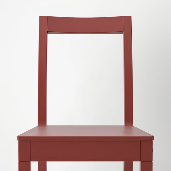 Silla de madera roja con respaldo y asiento rectangulares, perteneciente a la serie PINNTORP, caracterizada por su robusta artesanía y su diseño minimalista.