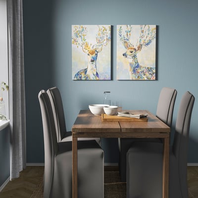 Comedor moderno con paredes azules, mesa de madera, sillas grises y dos lienzos de ciervos de colores.
