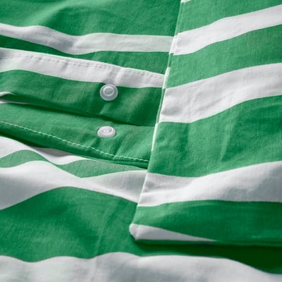 Primer plano de la ropa de cama de rayas verde-blancas, que muestra el cierre de botón a presión de plástico.