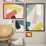 Pared de galería moderna con marcos RÖDALM en rojo, negro y madera natural, con diseños abstractos.