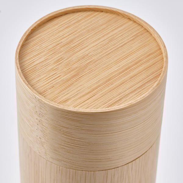 Recipiente cilíndrico de bambú con acabado liso y envejecido. La tapa se ajusta perfectamente, evocando el almacenamiento tradicional de té. El recubrimiento de laca transparente realza el grano natural.