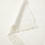 Manta de tejido blanco con bordes con flecos, suave y acogedora, perfecta para acurrucarse.