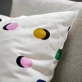 Cojín de lunares en sofá, fondo blanco con puntos de colores, diseño moderno.