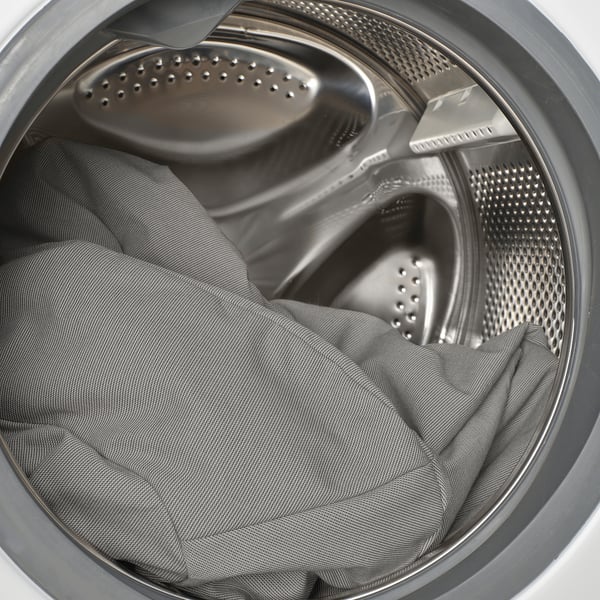 Lavadora abierta con pantalón oscuro en su interior, enfatizando la facilidad de carga y descarga.