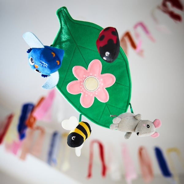 Móvil colorido con búho, mariquita, abeja y ratón que cuelga de una hoja verde con flor, estimulando la visión y la curiosidad del bebé.