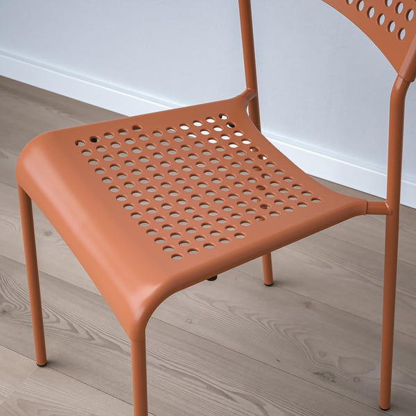 Silla de plástico naranja con orificios de ventilación, moderna y duradera