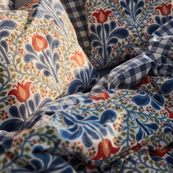 Edredón y almohadas con estampado floral brillante sobre una cama, mostrando diseños intrincados y colores vibrantes.