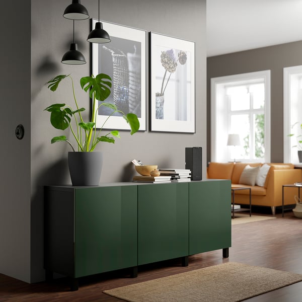 Sala de estar moderna con gabinete SELSVIKEN verde oliva oscuro, luces, plantas y cuadros.