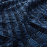 Edredón azul oscuro con costuras visibles, cuidadosamente doblado, que muestra tela de calidad y artesanía.