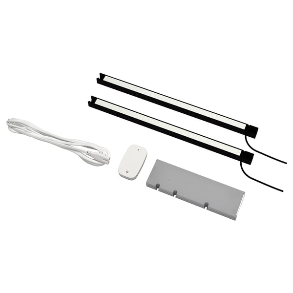 La imagen muestra el kit de iluminación de cocina LED SKYDRAG en blanco y negro, que contiene dos tiras de luz, un control remoto, una caja de controladores y un cable de alimentación blanco.