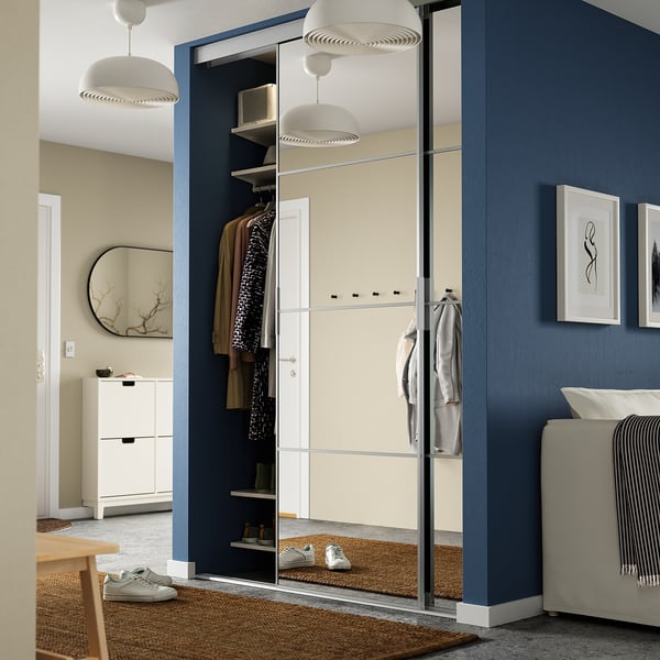 Armario SOTTTA, puerta corredera azul oscuro, ropa, marco negro, luces altas y modernas.