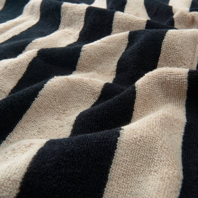 Una toalla SLÅNHÖSTMAL: rayas blancas y negras, forma rectangular, material de algodón suave.