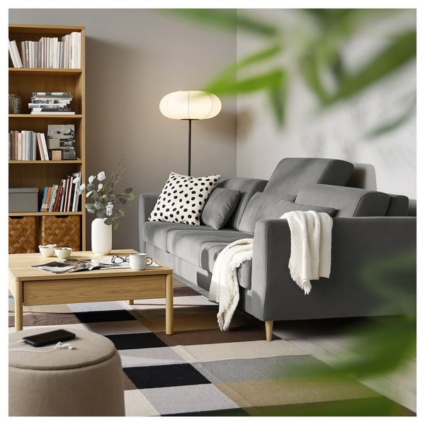 Sala de estar moderna con sofá SLATORP gris, almohadas de lunares, mesa de centro de madera, estantería y lámpara de pie.