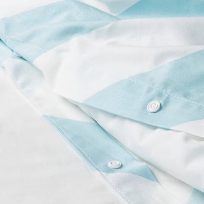 Primer plano de tejido de rayas celestes y blancas, con costuras finas y dos botones de presión blancos, que resaltan la calidad y el detalle.