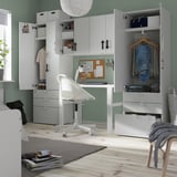 Habitación infantil con armarios blancos, ropa, estanterías, cajones. Escritorio y silla.