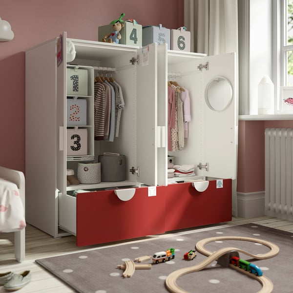 Armario infantil con estantes, cajones y perchas, organizado con cajas y juguetes sobre alfombra.