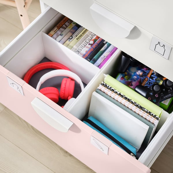 Abre los cajones de almacenamiento rosas que muestran auriculares, libros y estuches de videojuegos rojos.