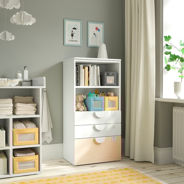 Un mueble de almacenamiento para niños SMÅSTAD blanco con estantes y cajones, que contiene juguetes y suministros en una habitación acogedora y bien iluminada.