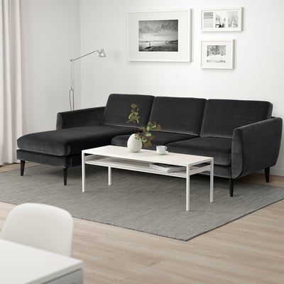 Moderno sofá modular gris con tumbona, mesa de centro blanca, arte en blanco y negro, alfombra gris, suelo de madera.